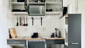 A compact kitchen with a microwave, sink, and a small refrigerator.