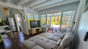 A modern living room with a grey sofa, a TV, and a dining area with a wooden table and chairs. - Villa Dali, 50 m from the beach, between Deshaie and Sainte Rose (Sainte-Rose)