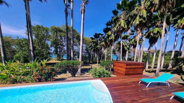 A wooden deck with a pool, lounge chairs, and palm trees. - Villa Dali, 50 m from the beach, between Deshaie and Sainte Rose (Sainte-Rose)