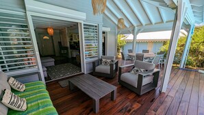 An outdoor covered patio with wooden flooring, a sofa, two armchairs, a coffee table, and a dining table with chairs. - Villa Dali, 50 m from the beach, between Deshaie and Sainte Rose (Sainte-Rose)