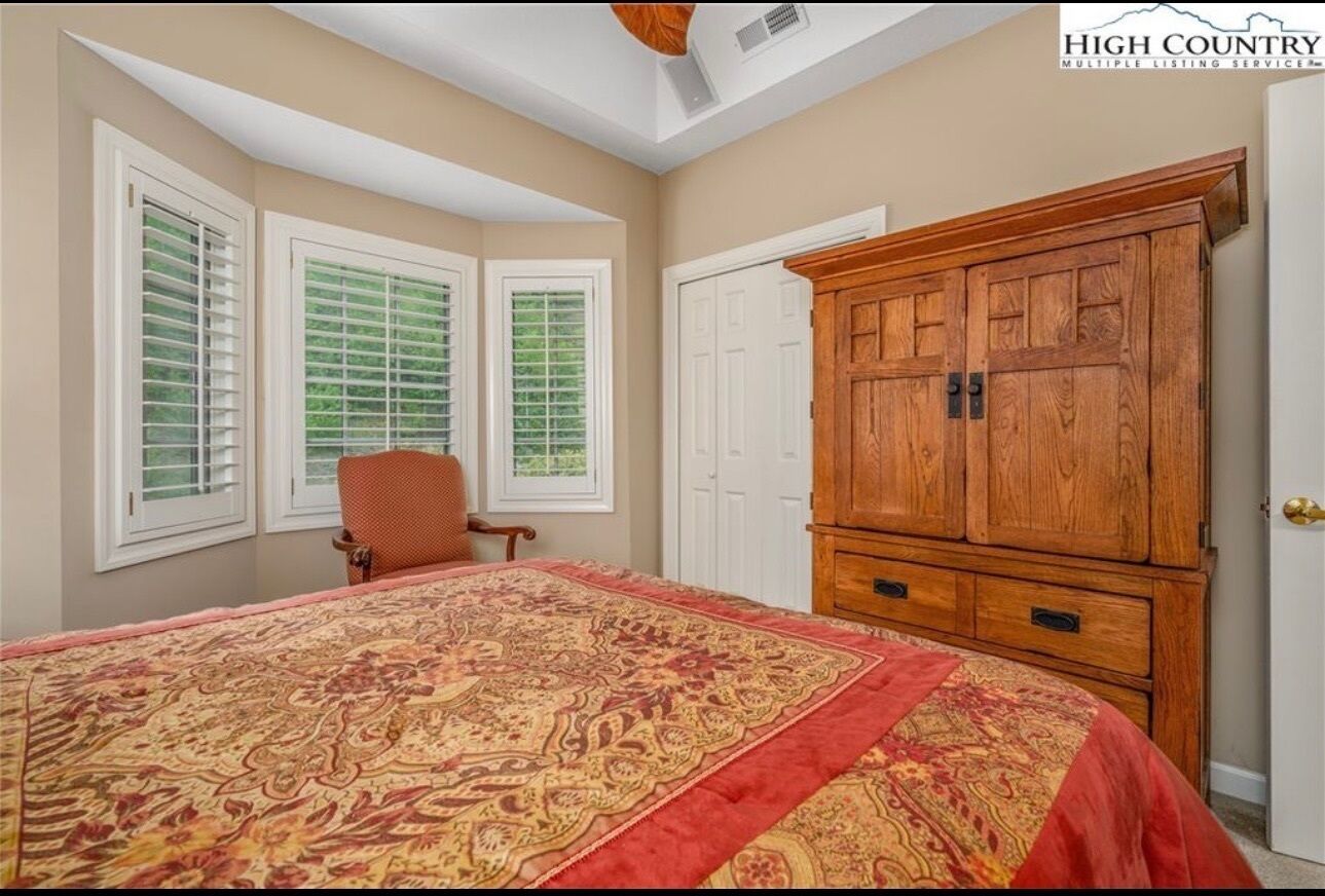 Une chambre avec un grand lit, une armoire en bois et une fenêtre avec des stores.