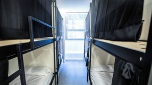 A corridor with bunk beds, a window at the end, and a tiled floor. - MYD Madriz Hostel (Madrid)