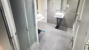 A modern bathroom with a glass shower enclosure, a white sink, and a toilet. - MYD Madriz Hostel (Madrid)