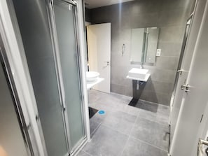 A modern bathroom with a glass shower enclosure, a white sink, and a toilet. - MYD Madriz Hostel (Madrid)