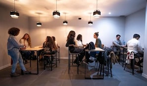 A modern interior with a group of people seated at tables, engaged in conversation. - MYD Madriz Hostel (Madrid)