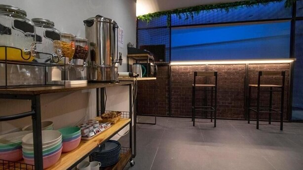 A modern kitchen with a brick wall, a bar area with stools, and a window with a view. - MYD Madriz Hostel (Madrid)
