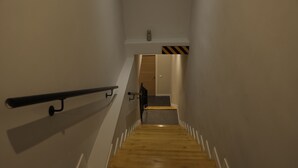 A narrow stairway with wooden steps and a metal handrail, leading to a door with a striped pattern. - MYD Madriz Hostel (Madrid)
