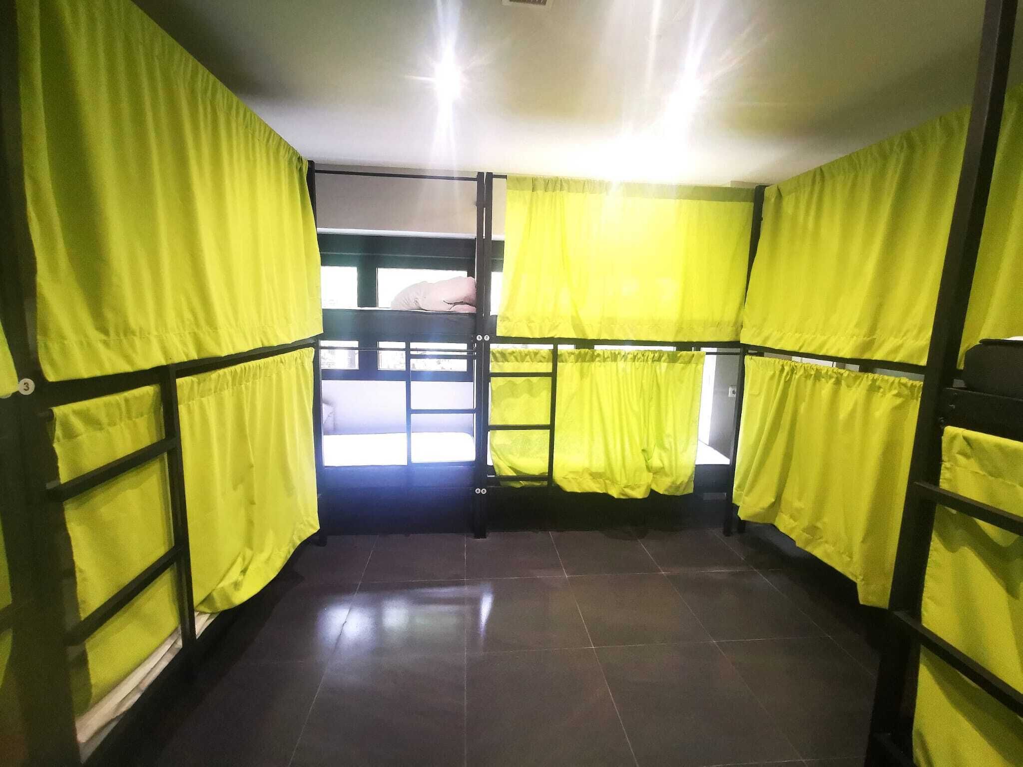 A room with bunk beds, yellow curtains, and a view of the outside.