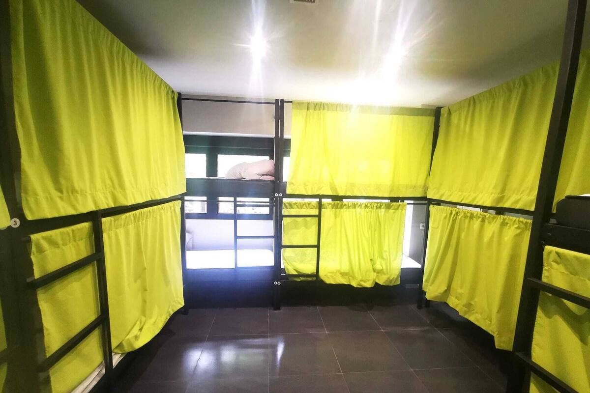 A room with bunk beds, yellow curtains, and a view of the outside.
