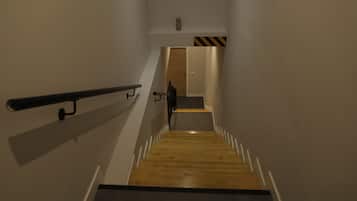 Un escalier étroit, doté d’une main courante d’un côté et d’un plancher en bois.