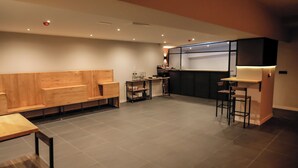 A modern kitchen with a wooden bench seating area, a bar counter, and a small kitchenette. - MYD Madriz Hostel (Madrid)