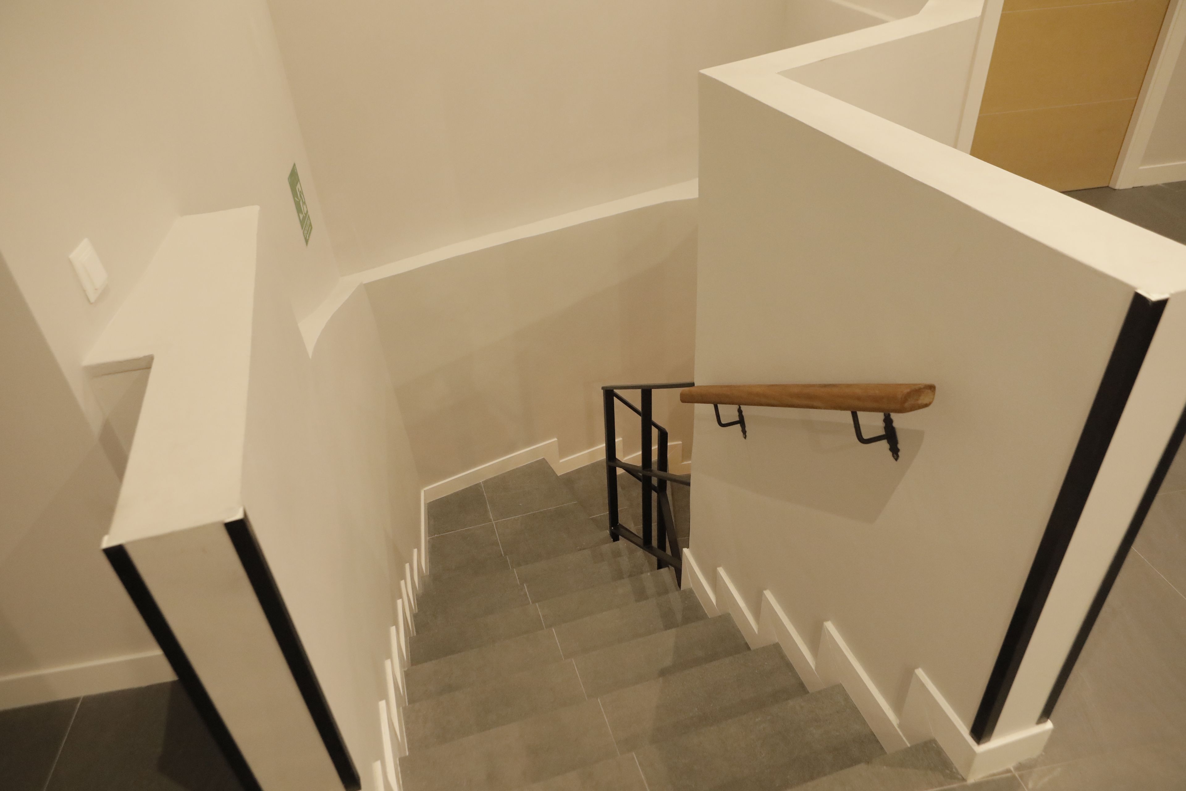 A staircase with a handrail and a black metal railing.