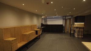 A modern interior with wooden benches and a kitchen area. - MYD Madriz Hostel (Madrid)
