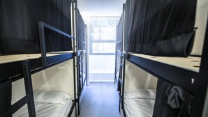 A corridor with bunk beds, a window at the end, and a tiled floor. - MYD Madriz Hostel (Madrid)