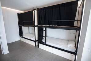 Une chambre avec deux lits superposés, chacun doté d’un compartiment de rangement en dessous.