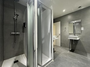 A modern bathroom with a glass-enclosed shower, a sink, and a mirror. - MYD Madriz Hostel (Madrid)