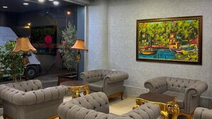 A room with grey upholstered armchairs, a round table, and a colorful painting on the wall. -  ADANA KOZA HOTEL (Adana)