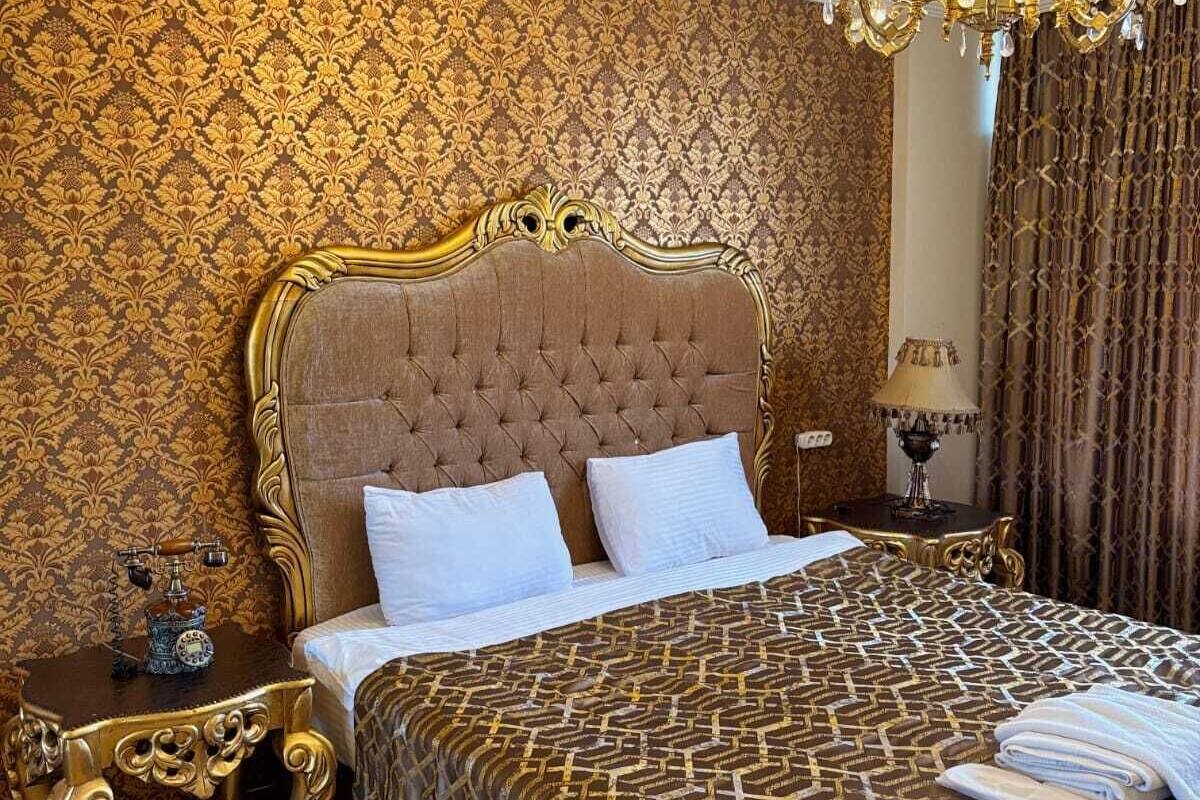 A luxurious bedroom with a tufted headboard, a patterned bedspread, and a chandelier.