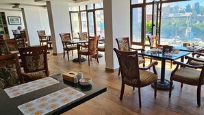A spacious dining area with wooden tables and chairs, large windows offering a view of the city, and a clean, modern interior design. -  ADANA KOZA HOTEL (Adana)