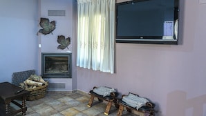 Una sala de estar con chimenea, televisor montado en la pared y un ventanal con cortinas.