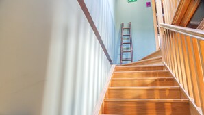 Una escalera de madera con barandilla de metal que sube a un rellano con barandilla de madera.