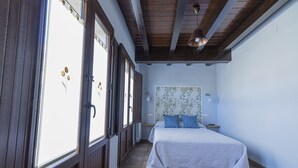 Un dormitorio con cama, ventana y techo de madera.