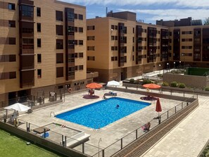 Un edificio moderno con piscina, zona de estar exterior y área cercada.