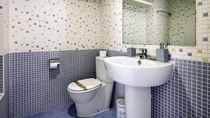 Et badeværelse med en hvid vask, toilet og spejl.