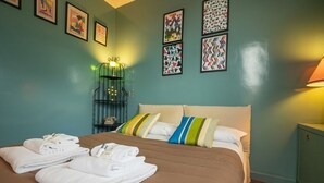 A hotel room with a bed, towels, pillows, a nightstand, a lamp, and wall art. - Tiffany's Apartment Flaminio (Roma)