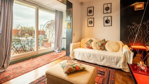 A living room with a sofa, ottoman, and a large window. - Tiffany's Apartment Flaminio (Roma)