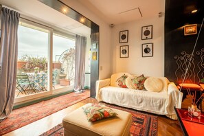 A living room with a sofa, ottoman, and a large window. - Tiffany's Apartment Flaminio (Roma)