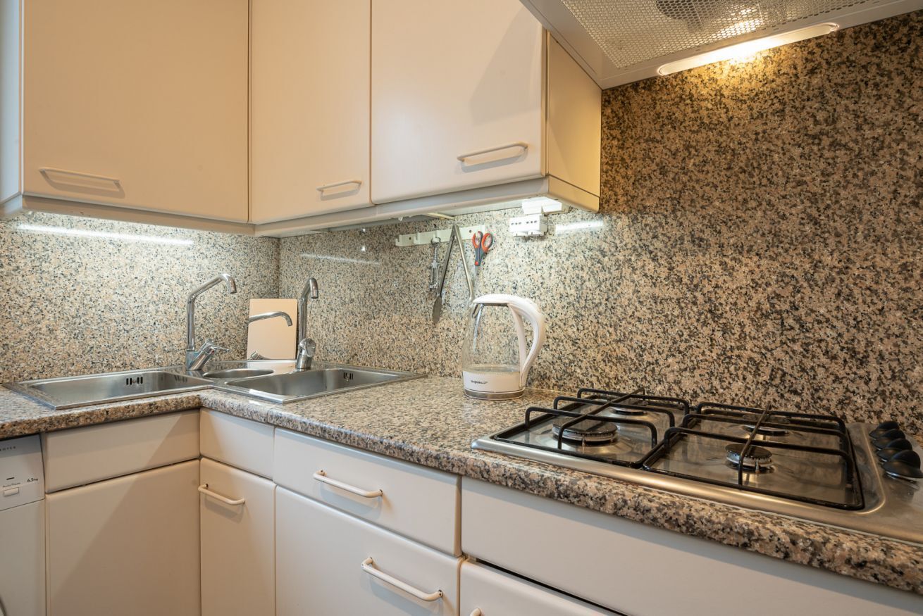 A kitchen with granite countertops, stainless steel appliances, and white cabinetry.