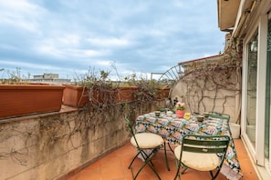 Une terrasse avec une table et des chaises, une plante en pot et une vue sur la ville.