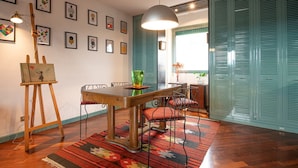 A dining area with a wooden table, chairs, a hanging light, and artwork on the walls. - Tiffany's Apartment Flaminio (Roma)