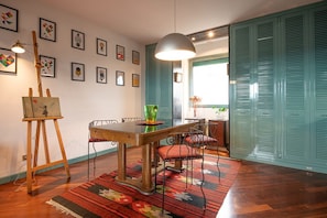 Un coin repas avec une table en bois, des chaises, une lampe suspendue et des œuvres d’art accrochées aux murs.