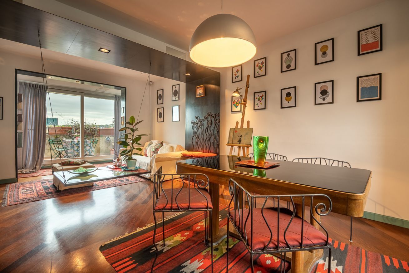 A modern living room with a dining area, large windows, and a view of the city.