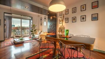 A modern living room with a dining area, large windows, and a view of the city.