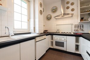 Una cocina con armarios blancos, encimera negra, ventana, estufa y platos decorativos en la pared.