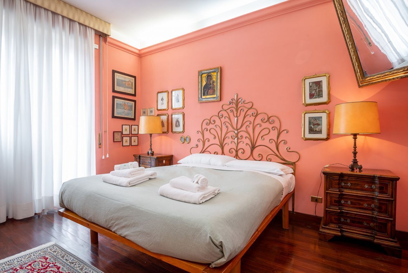 A bedroom with a bed, a nightstand, a dresser, and a mirror.