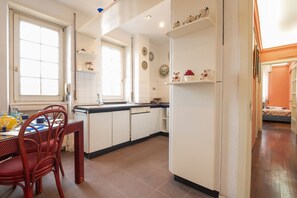 Una cocina con armarios blancos, una mesa de comedor con sillas y un refrigerador.