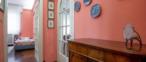 Una habitación con un aparador de madera, una puerta con paneles de vidrio y una pared decorada con platos azules.