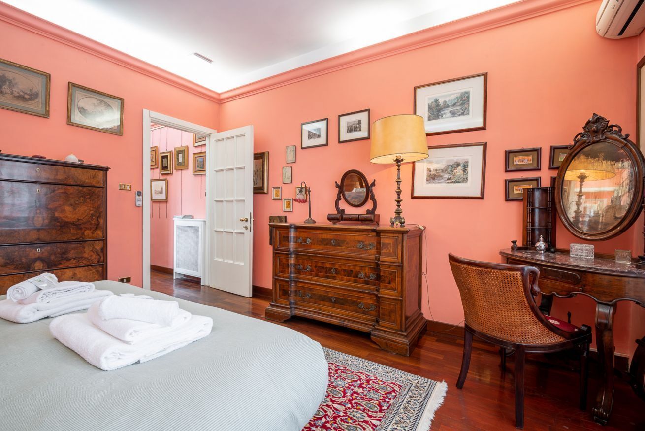 Un dormitorio con cama, cómoda, silla, escritorio y espejo.