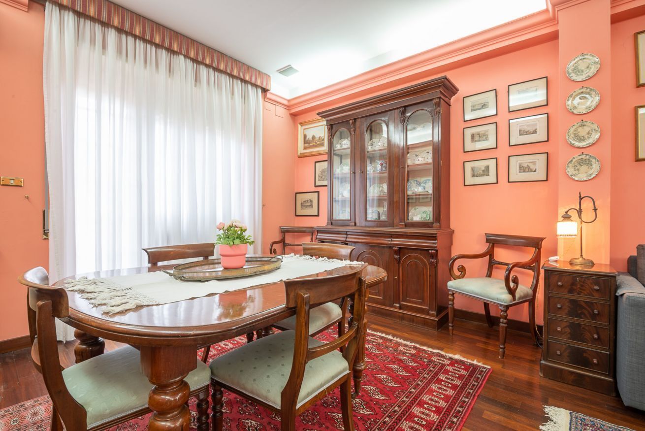 A dining room with a wooden table, chairs, a cabinet, and a rug.