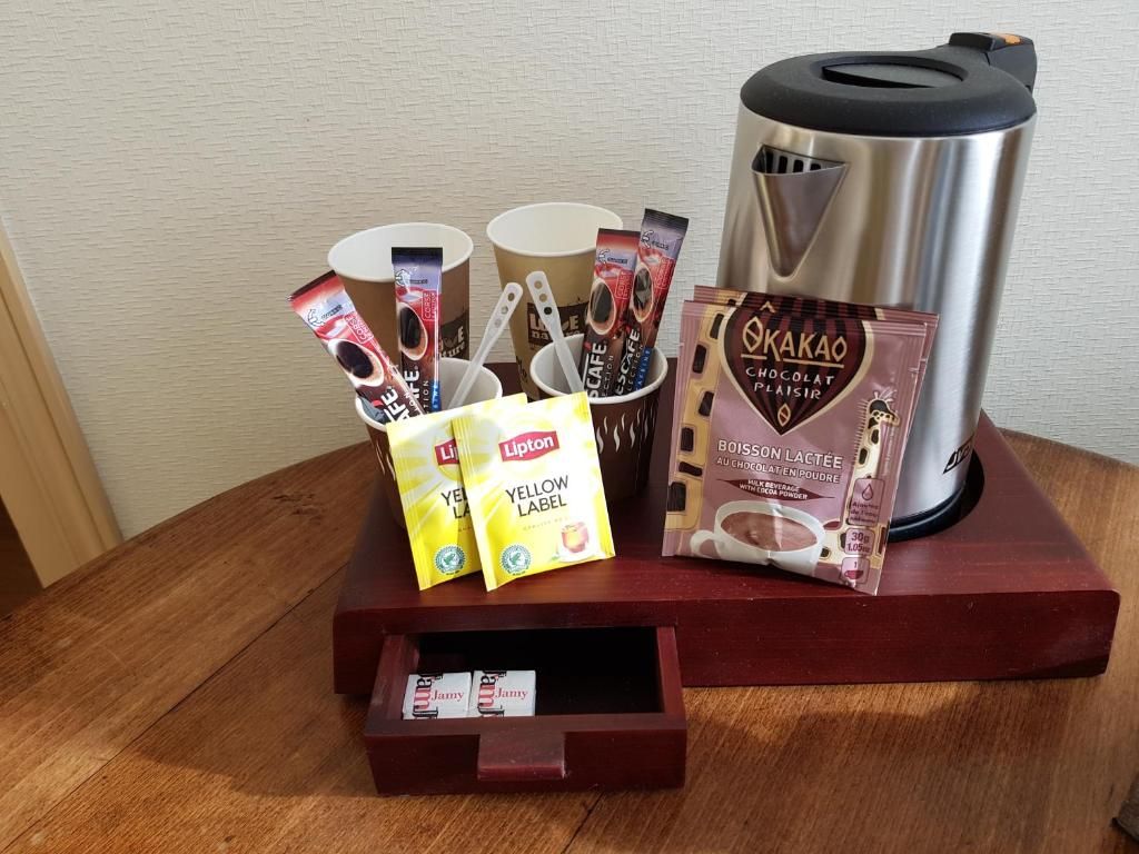 A coffee station with a coffee maker, cups, and chocolate bars.