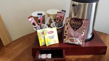 A coffee station with a coffee maker, cups, and chocolate bars.