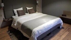 Un dormitorio moderno con una cama grande, dos mesitas de noche y un televisor montado en la pared.