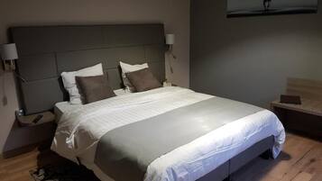 A modern bedroom with a large bed, two bedside tables, and a wall-mounted TV.