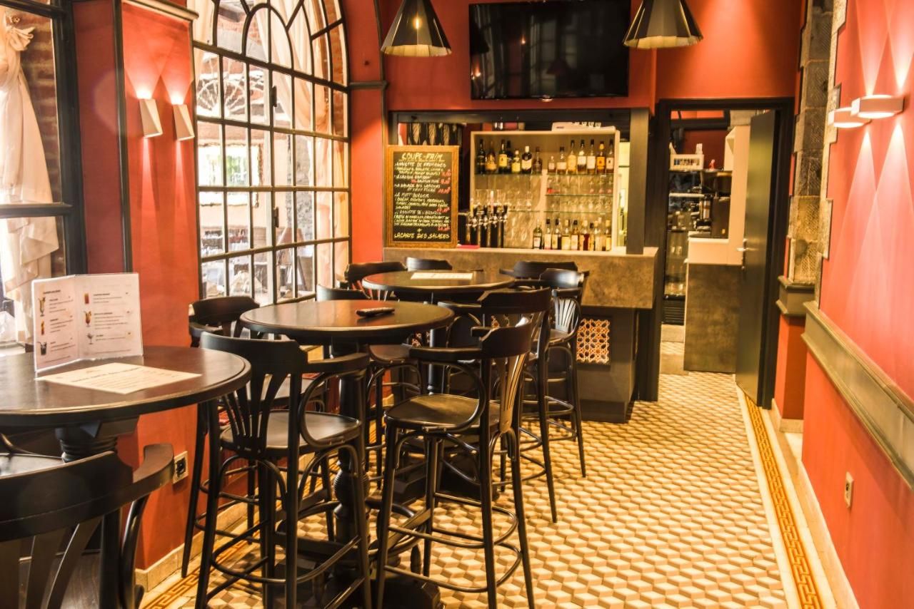 A bar area with round tables and chairs, a menu board, and a bar stocked with bottles.