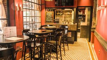 A bar area with round tables and chairs, a menu board, and a bar stocked with bottles.