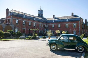 A historic building with a large courtyard and a vintage car parked in front. - Hotel Du Chateau De La Motte (Liessies)